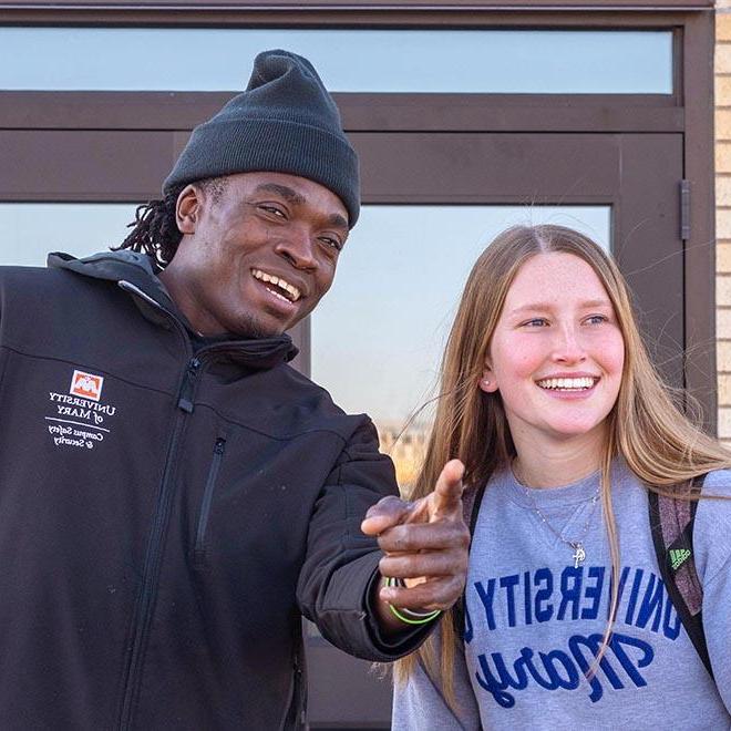 Campus safety and security employee pointing and giving a University of Mary student directions.